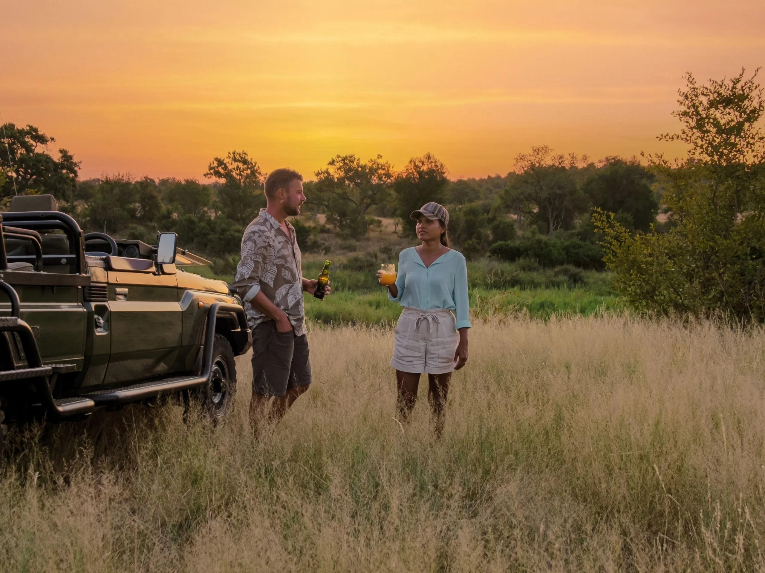 Hombre y mujer de safari por Sudáfrica, de pie al lado del jeep