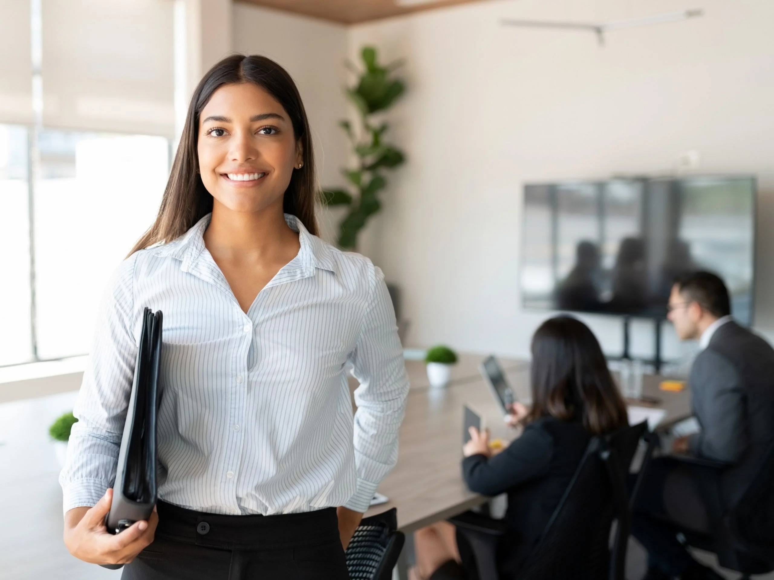 Mujer profesional en una oficina, sonriendo a cámara