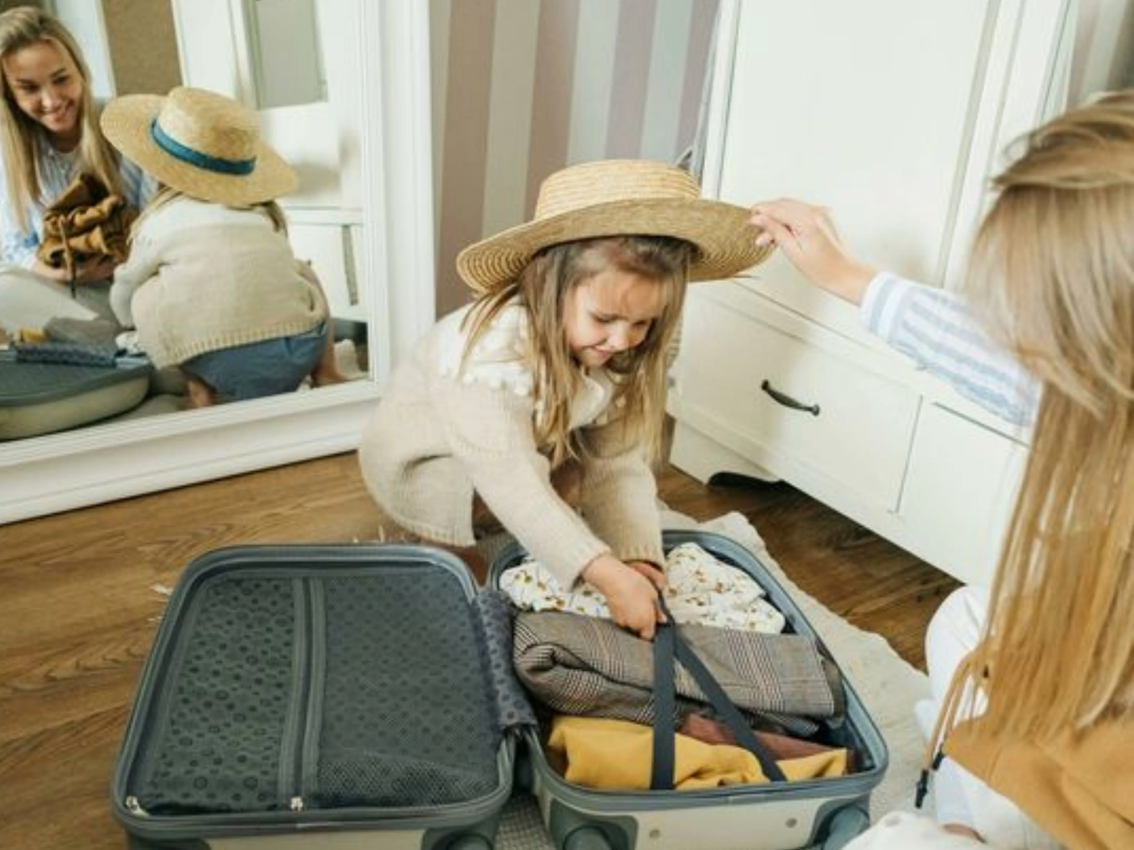 Una mujer y una niña pequeña están colocando ropa en una maleta