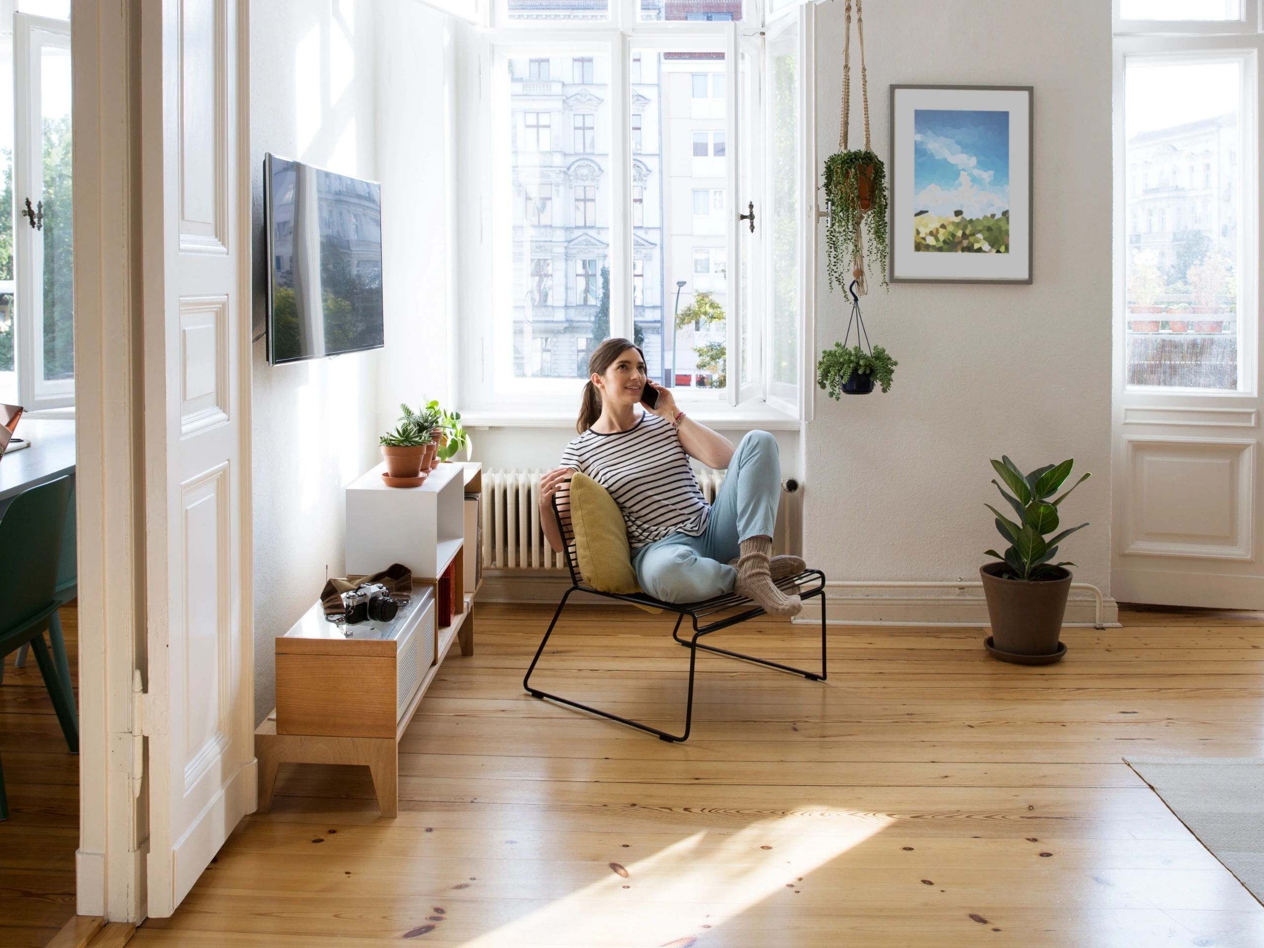 Mujer hablando por teléfono en el salón de su casa recostada en un sofá