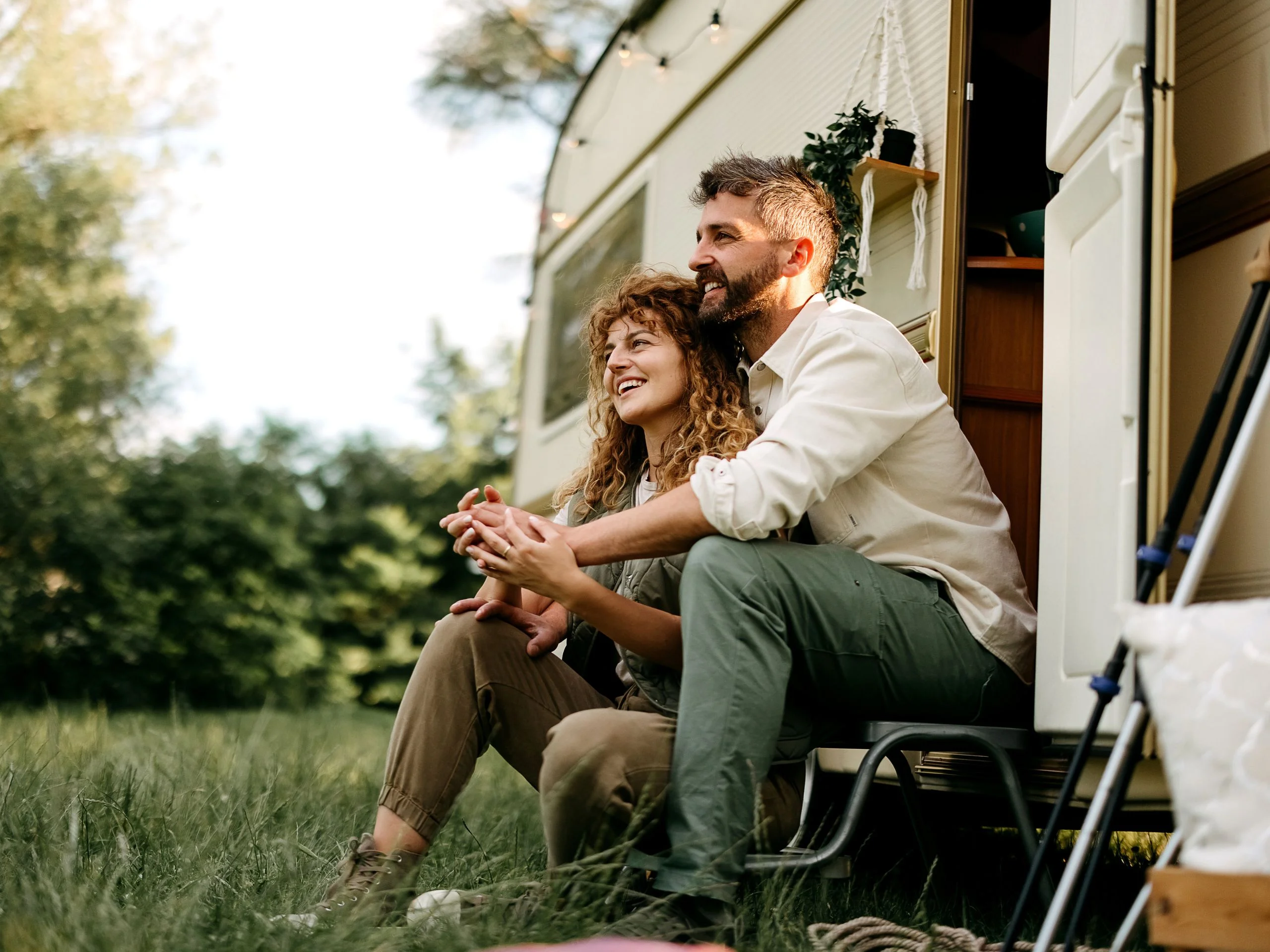 Pareja de hombre y mujer sentados en la entrada de su autocaravana