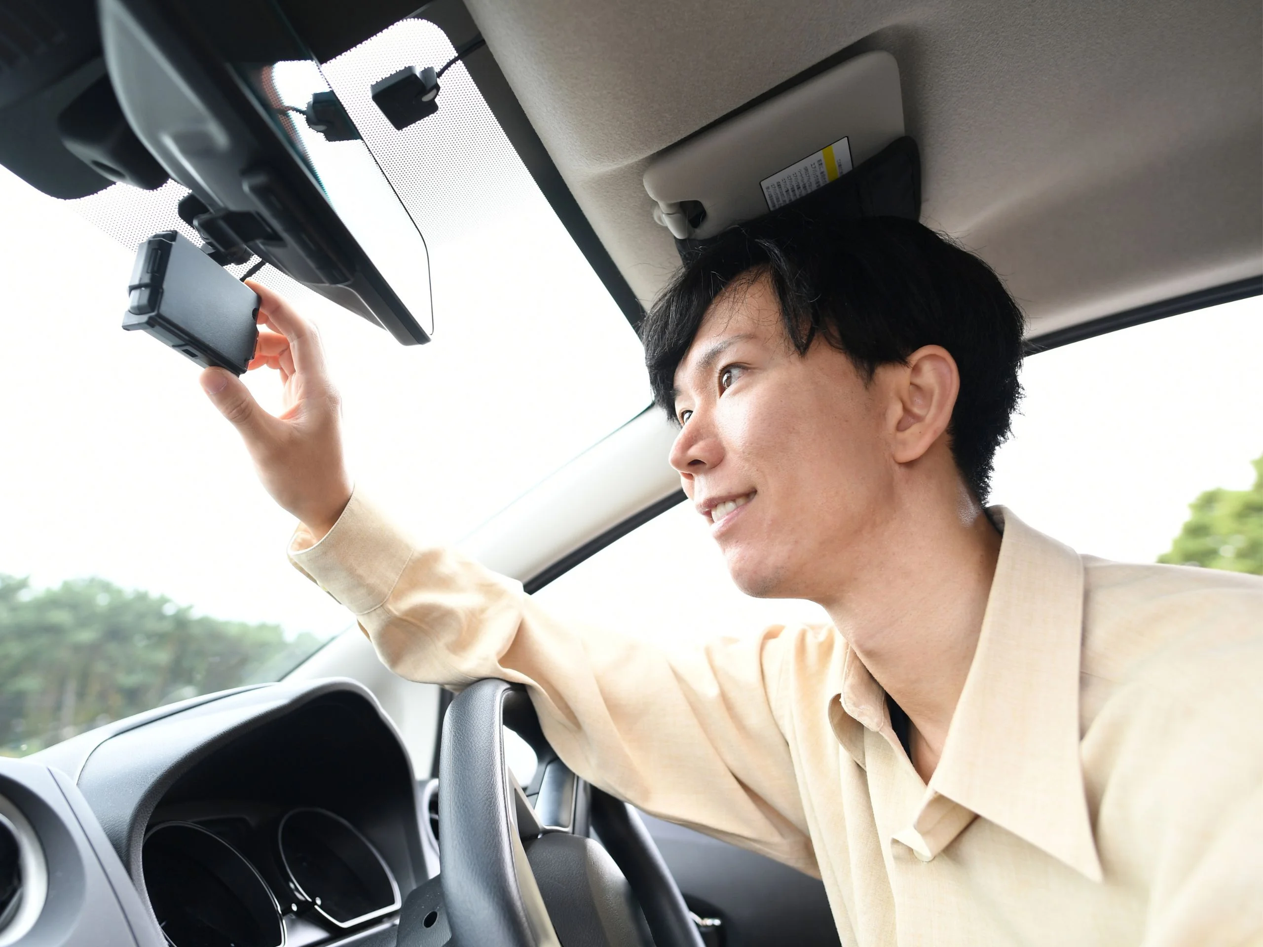 Joven asiático instalando una dashcam en el interior de su coche