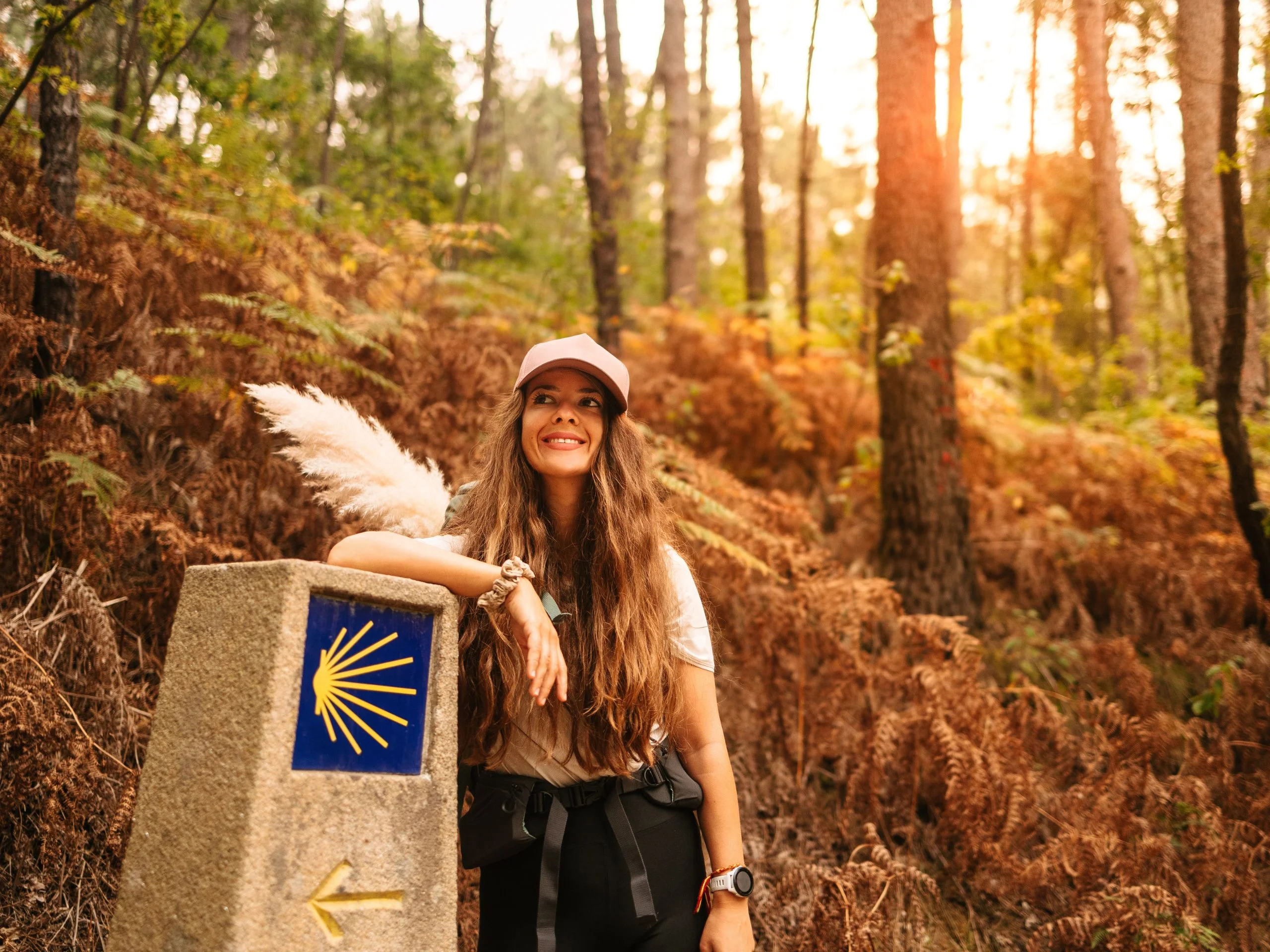 Mujer peregrina apoyada en señal del Camino de Santiago