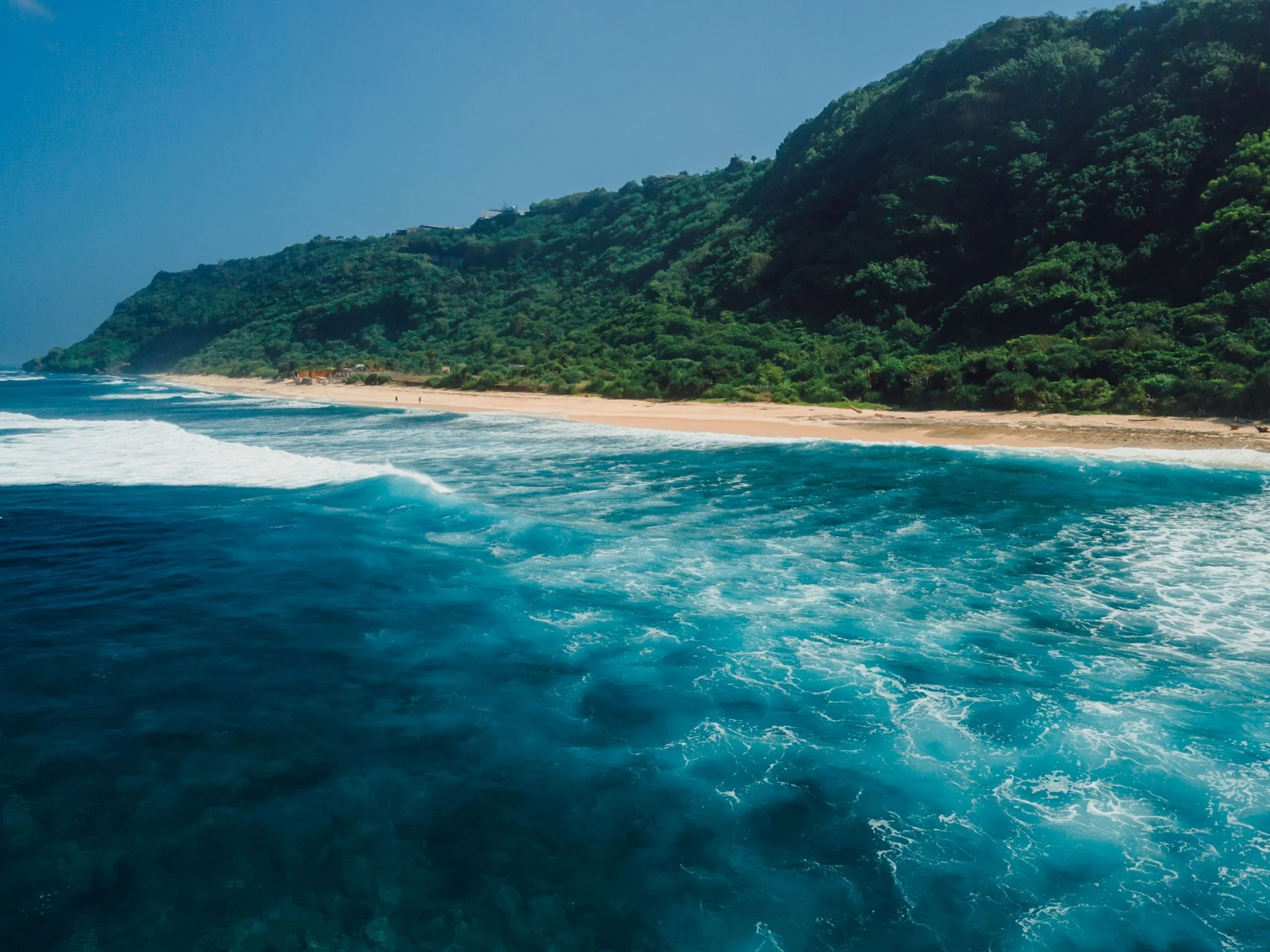 Vista desde el océano desde la costa de la playa con colinas verdes en Bali.