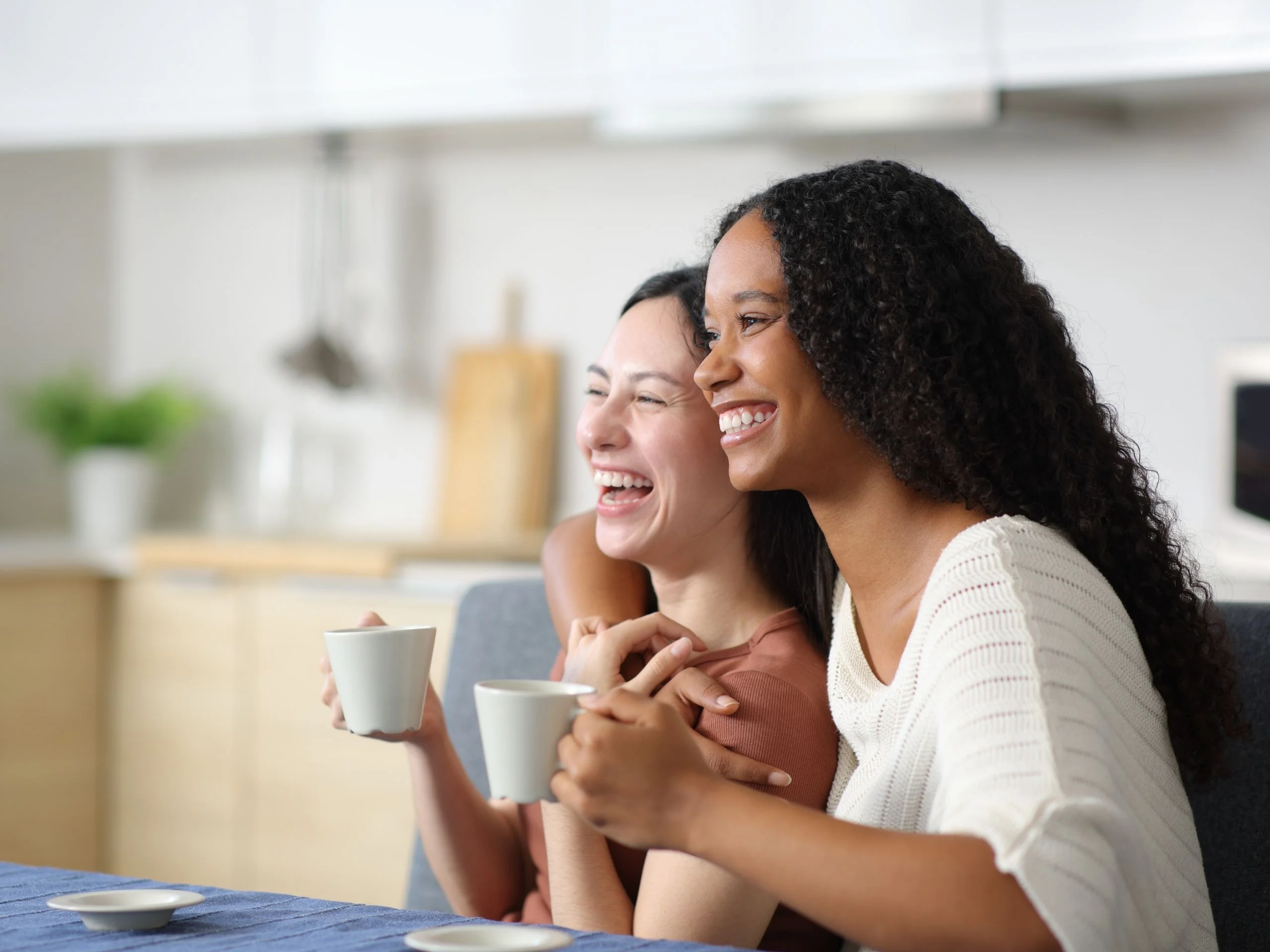 Dos mujeres jóvenes tomando café y sonriendo
