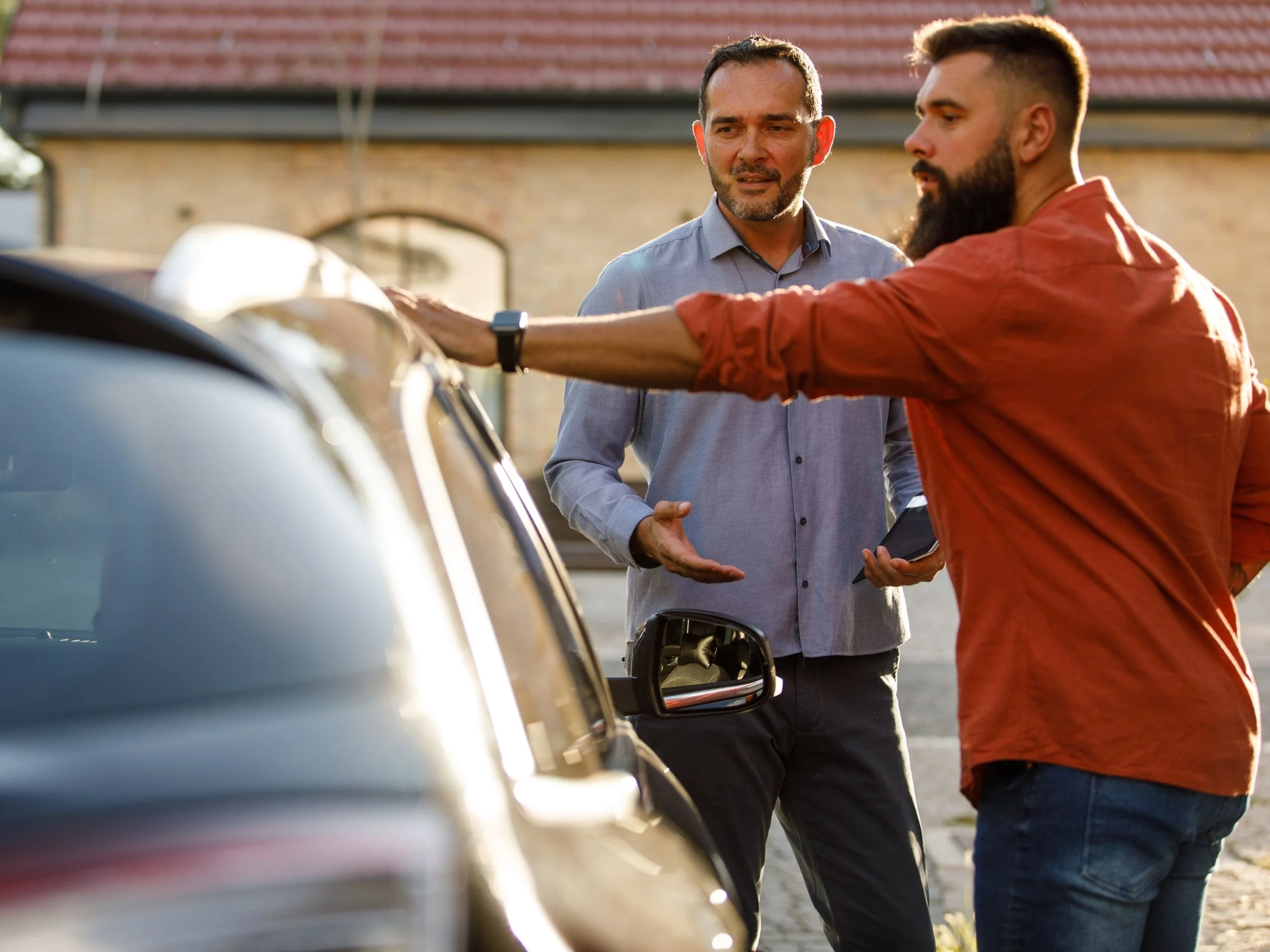 Dos hombres hablando al lado de un coche de segunda mano