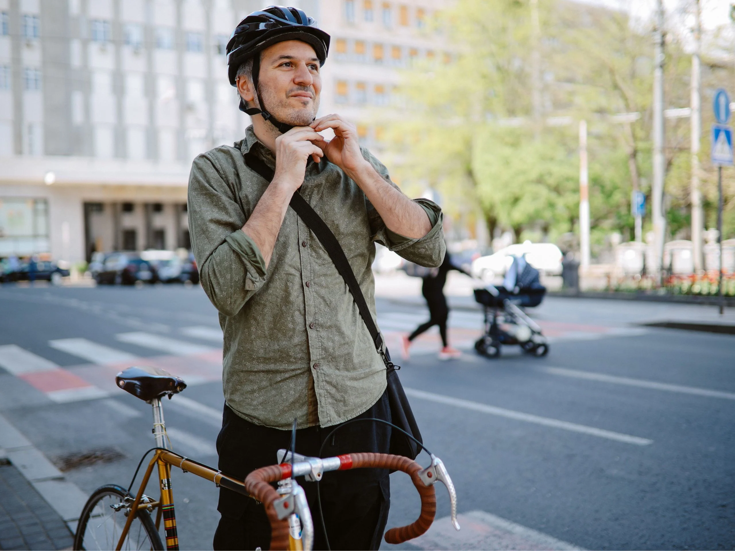 Hombre poniéndose casco para ir con bici por la ciudad
