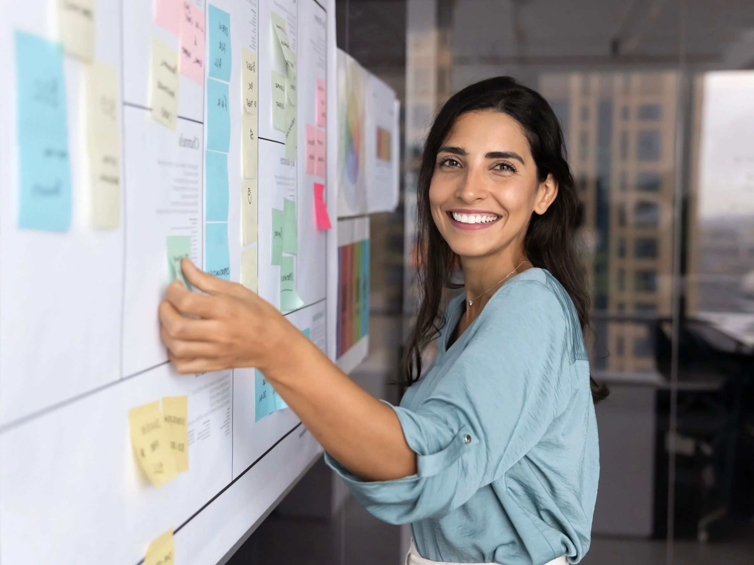 Mujer poniendo notas adhesivas en una pizarra de la oficina