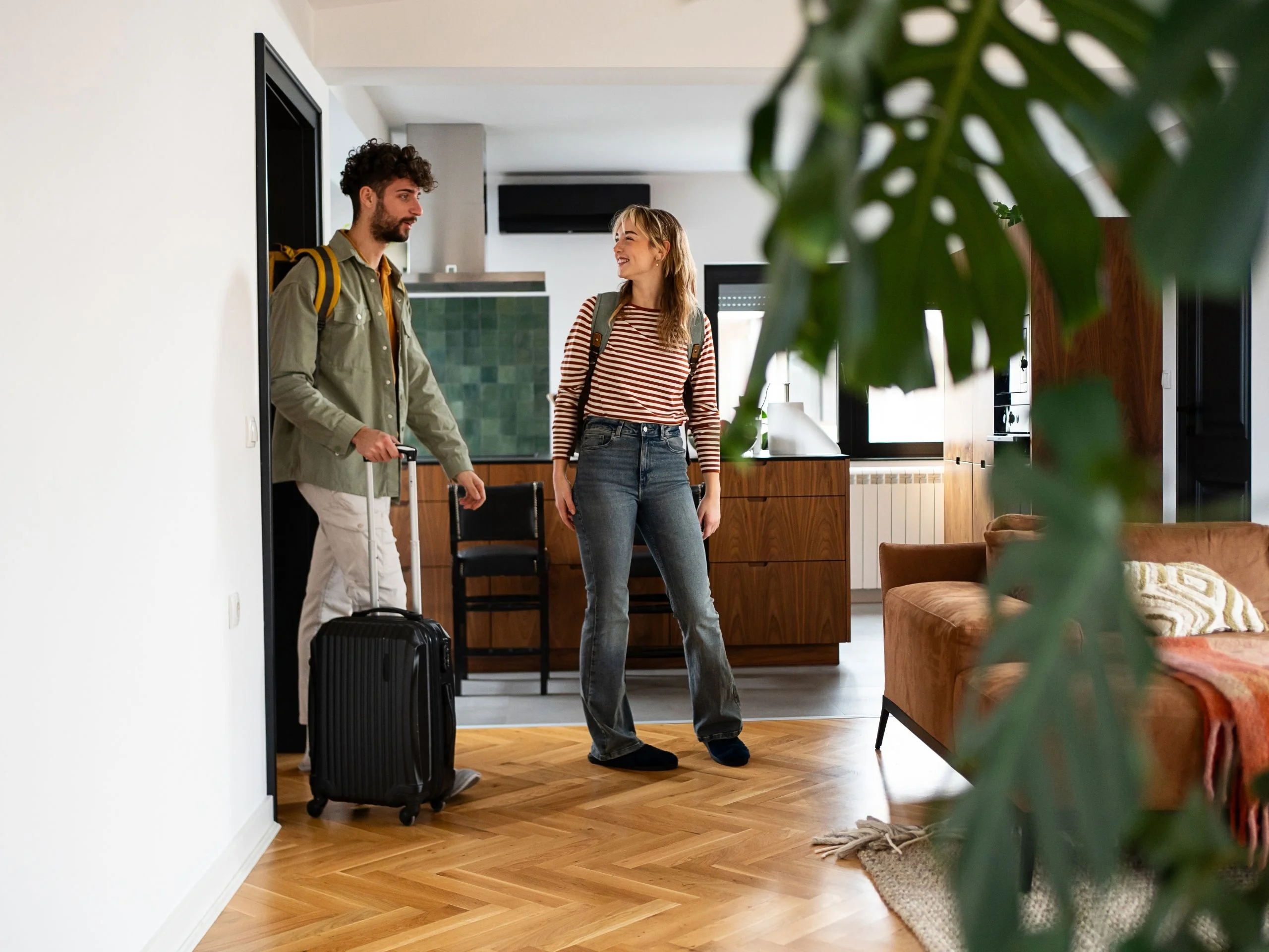 Joven pareja llegando a un acogedor apartamento con su equipaje