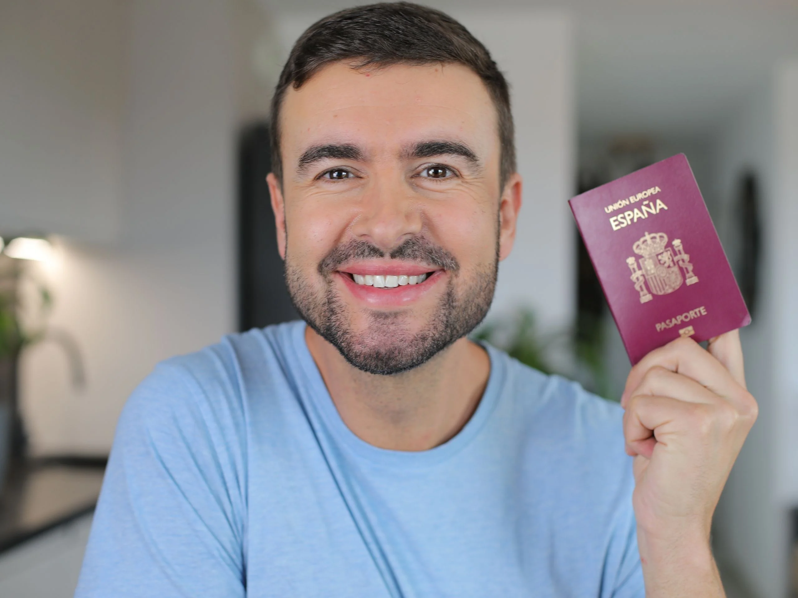 Hombre sosteniendo pasaporte español y sonriendo a cámara