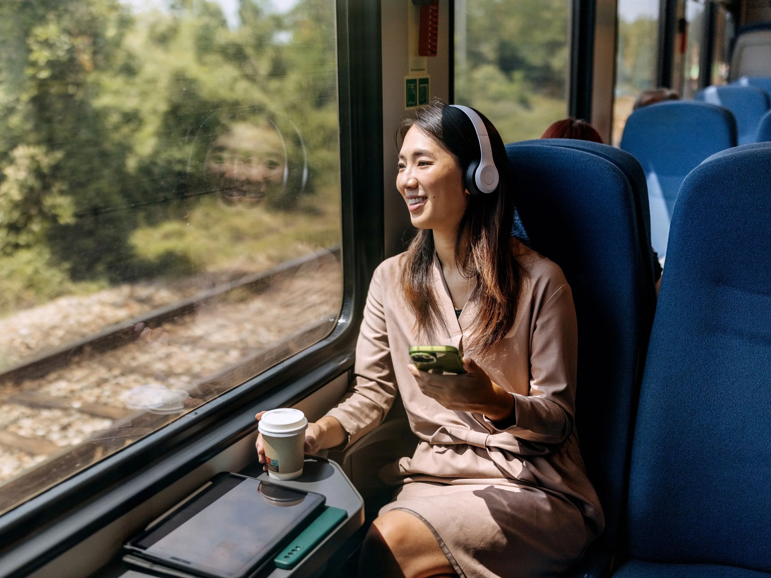 Mujer mirando por la ventana de un tren mientras toma un café un un sandwitch