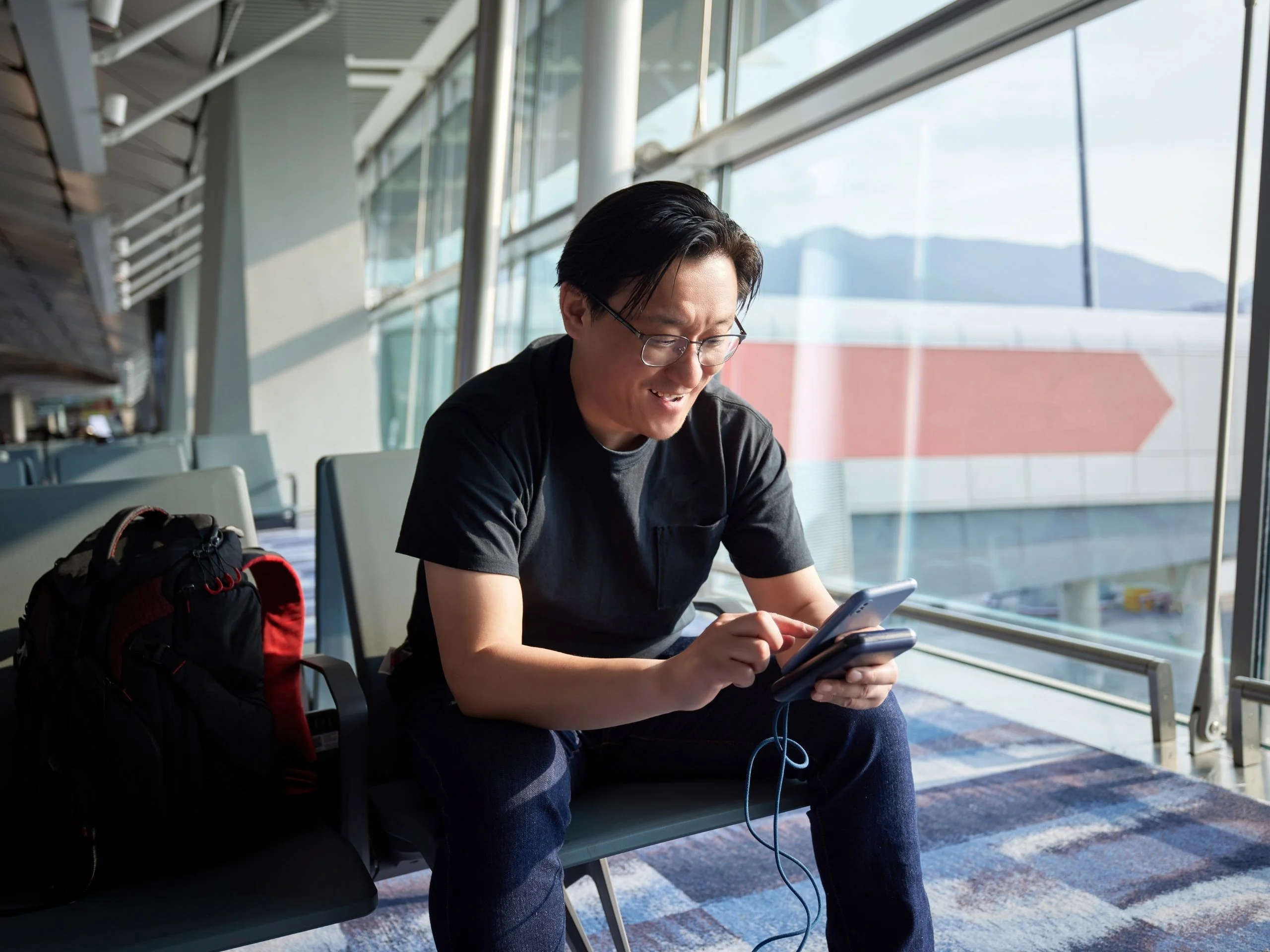 Hombre mirando su móvil mientras se carga con una power banken el aeropuerto