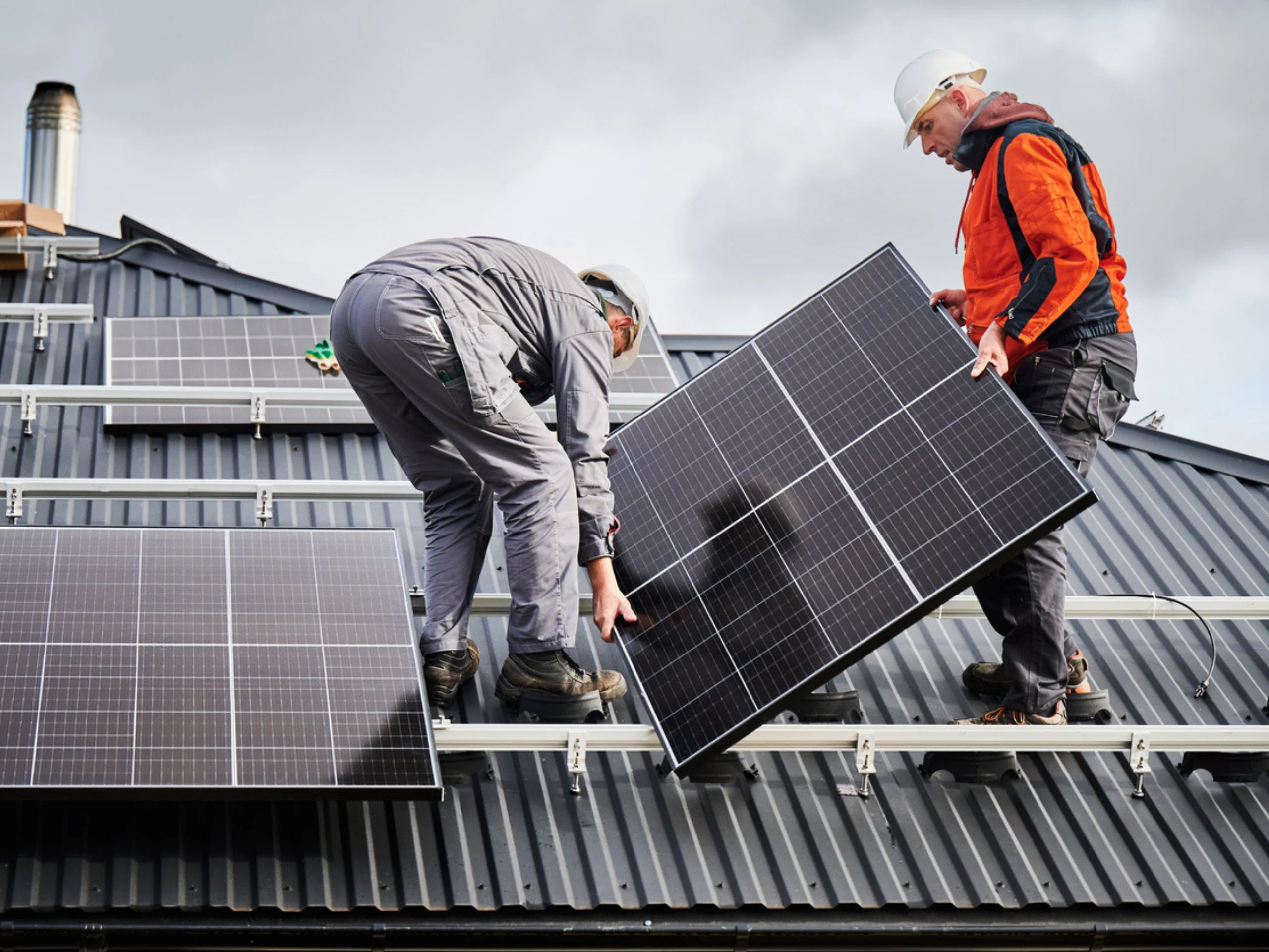 Dos hombres instalando placas solares en el techo de un edificio