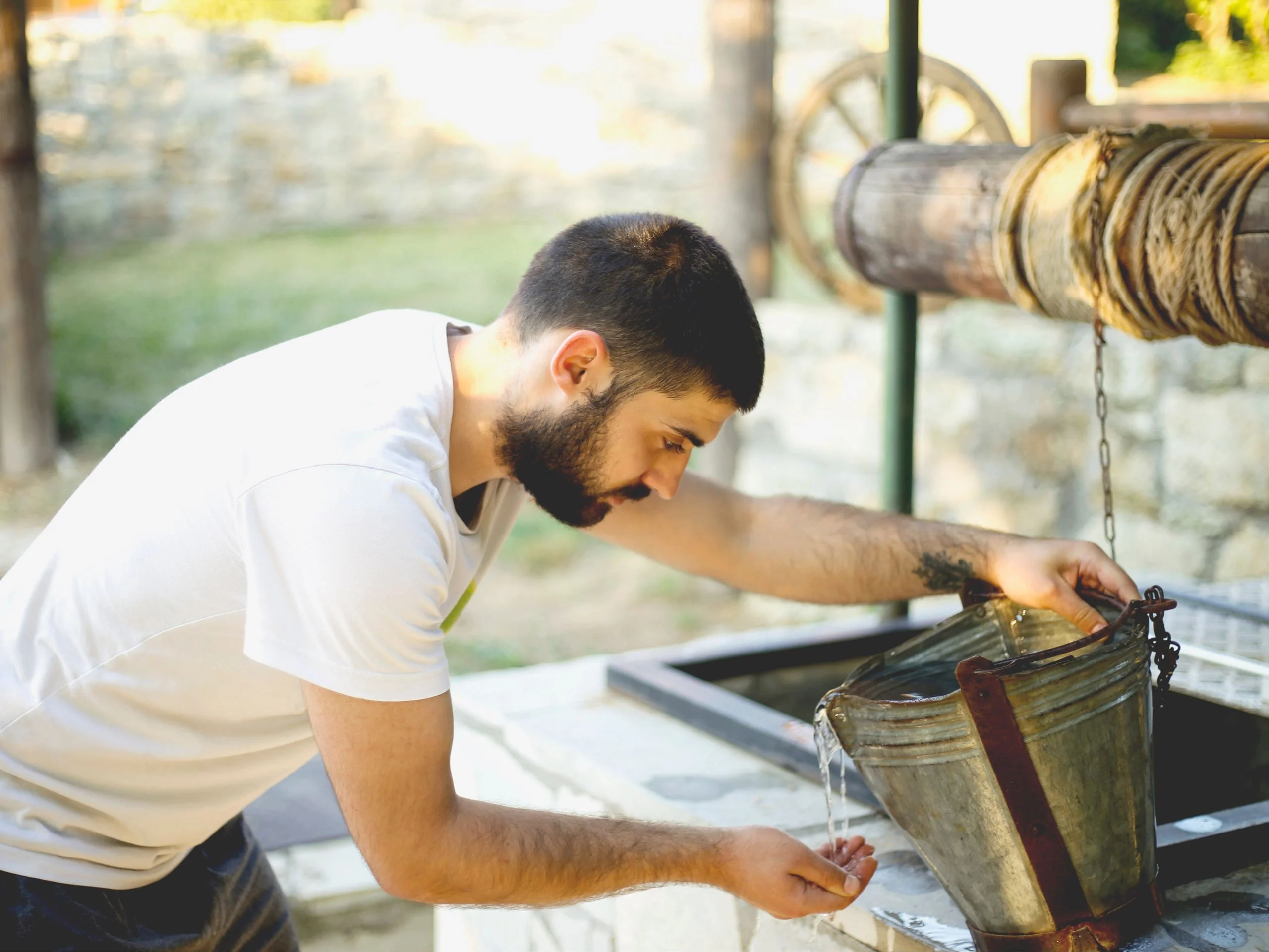 Hombre joven cogiendo agua de un pozo