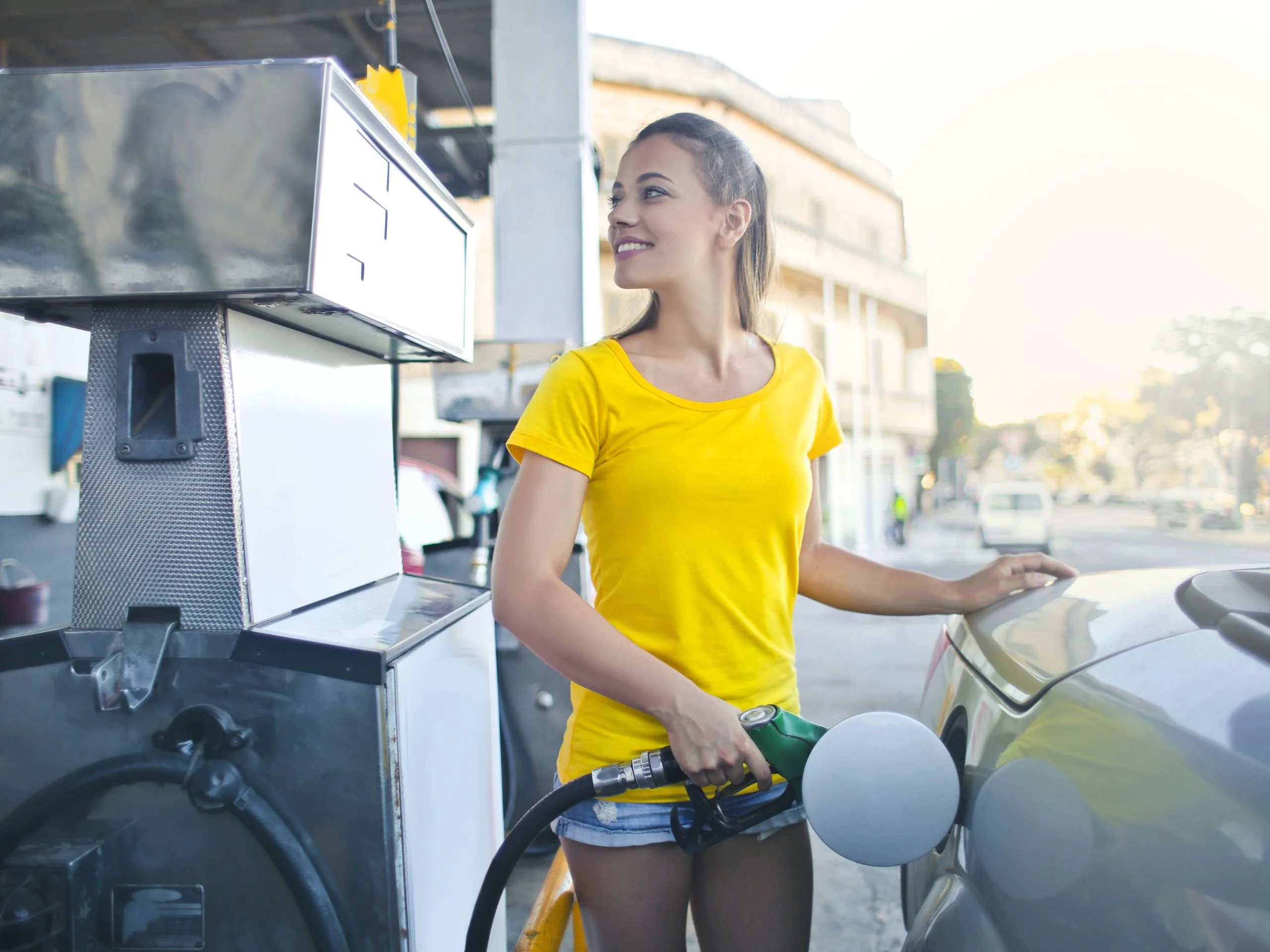 Mujer en gasolinera echando gasolina en su coche