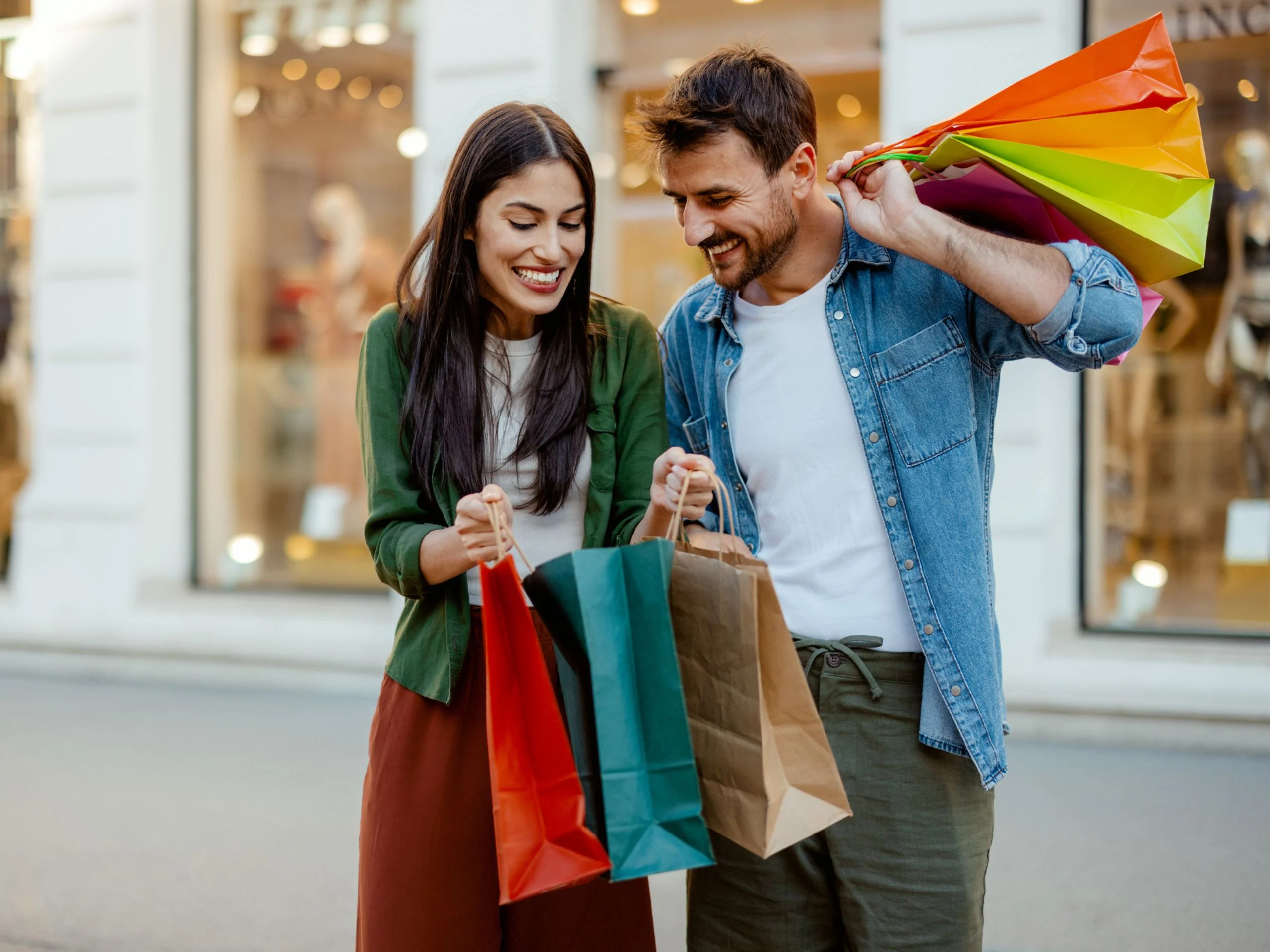 Hombre y mujer enseñándose sus compras en la calle