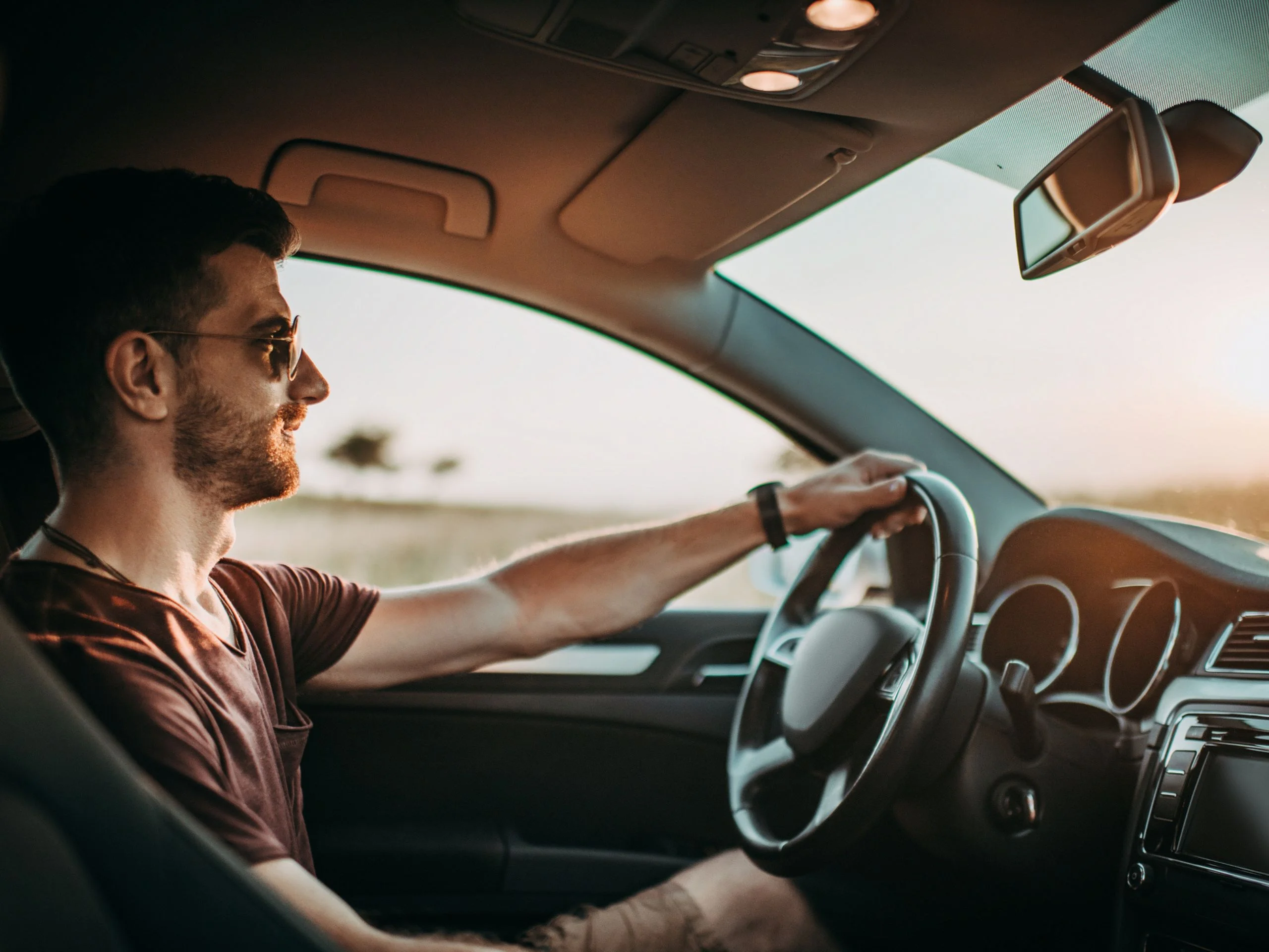 Hombre con gafas de sol conduciendo su coche