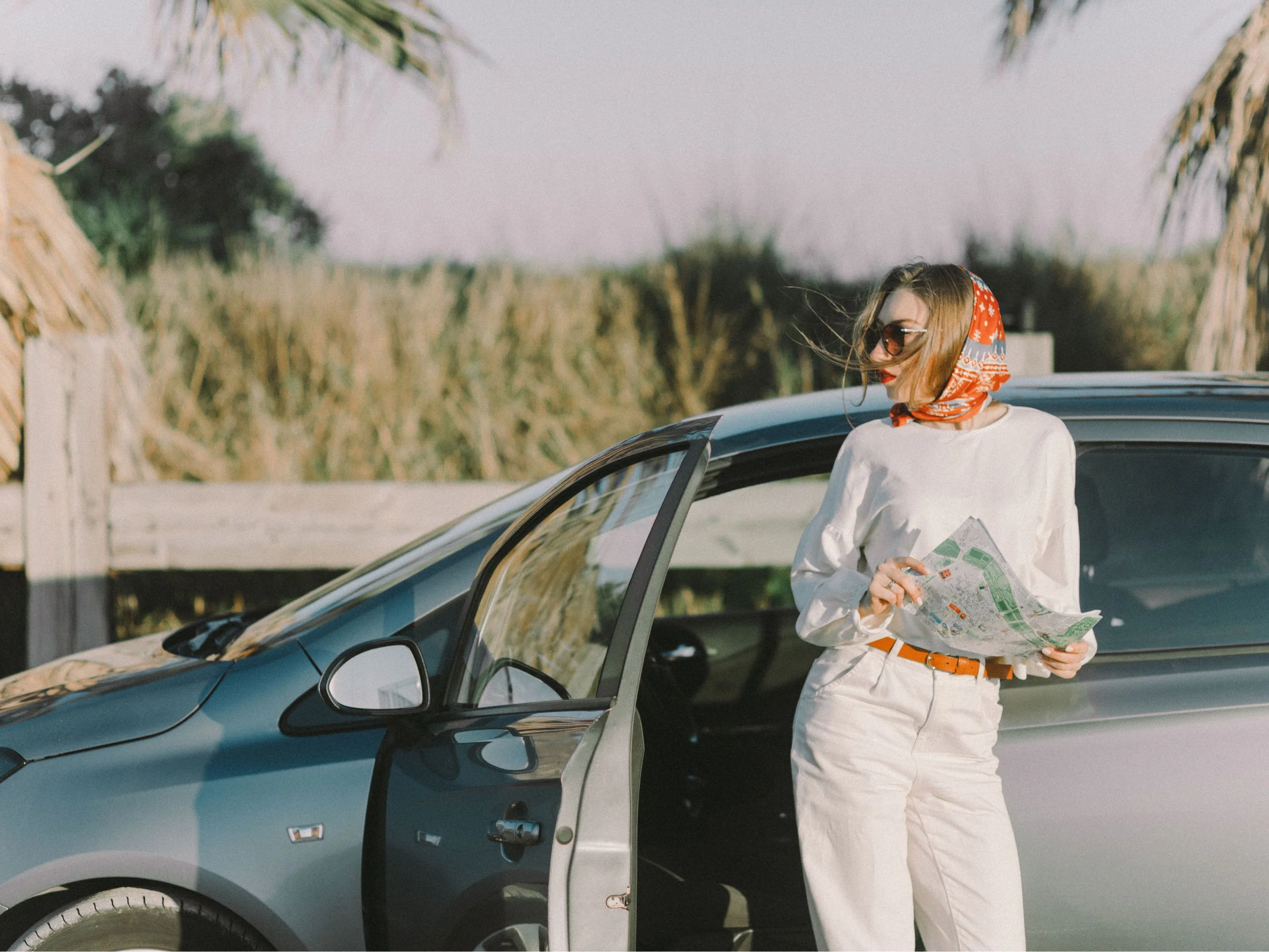 Mujer fuera de su coche, en la carretera, mirando un mapa