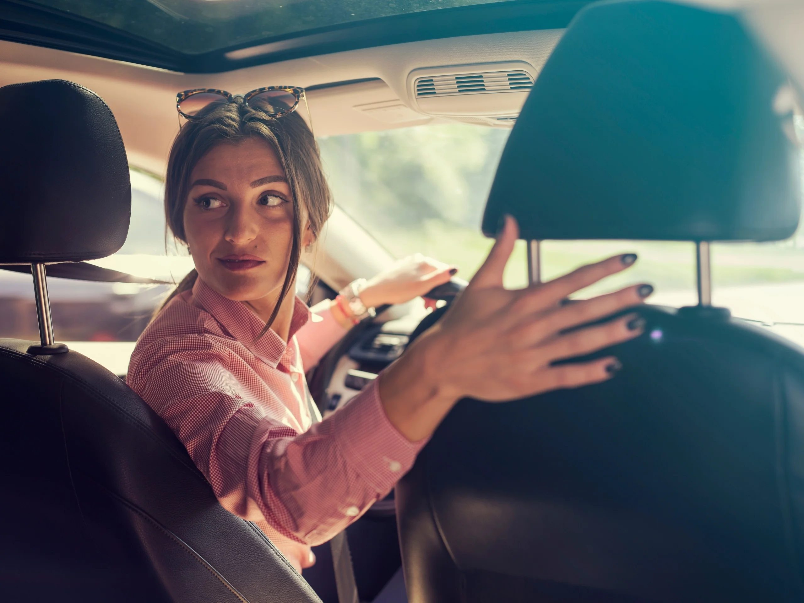 Mujer en coche mirando hacía atrás para aparcar