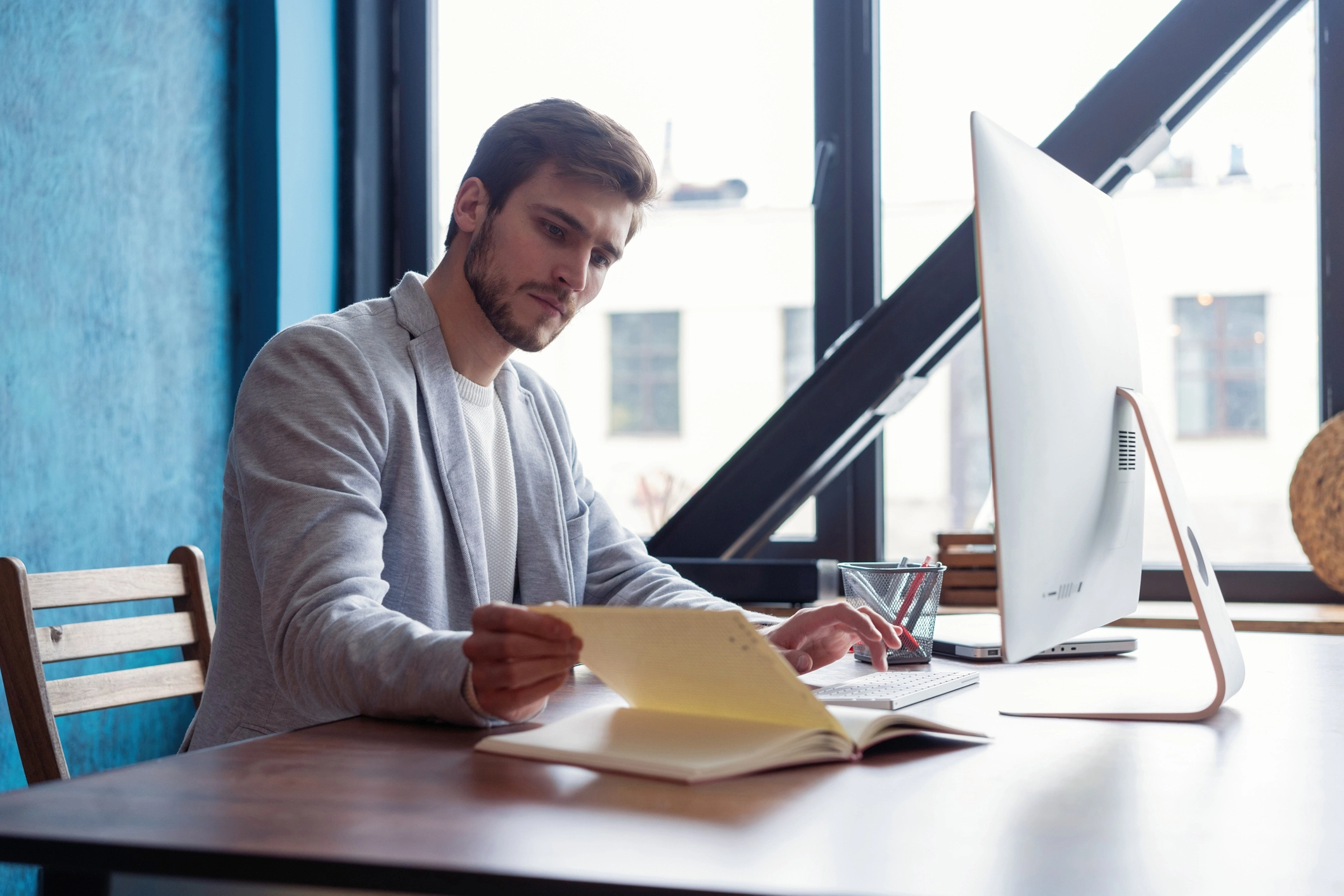 Hombre oficinista mirando libreta delante del ordenador