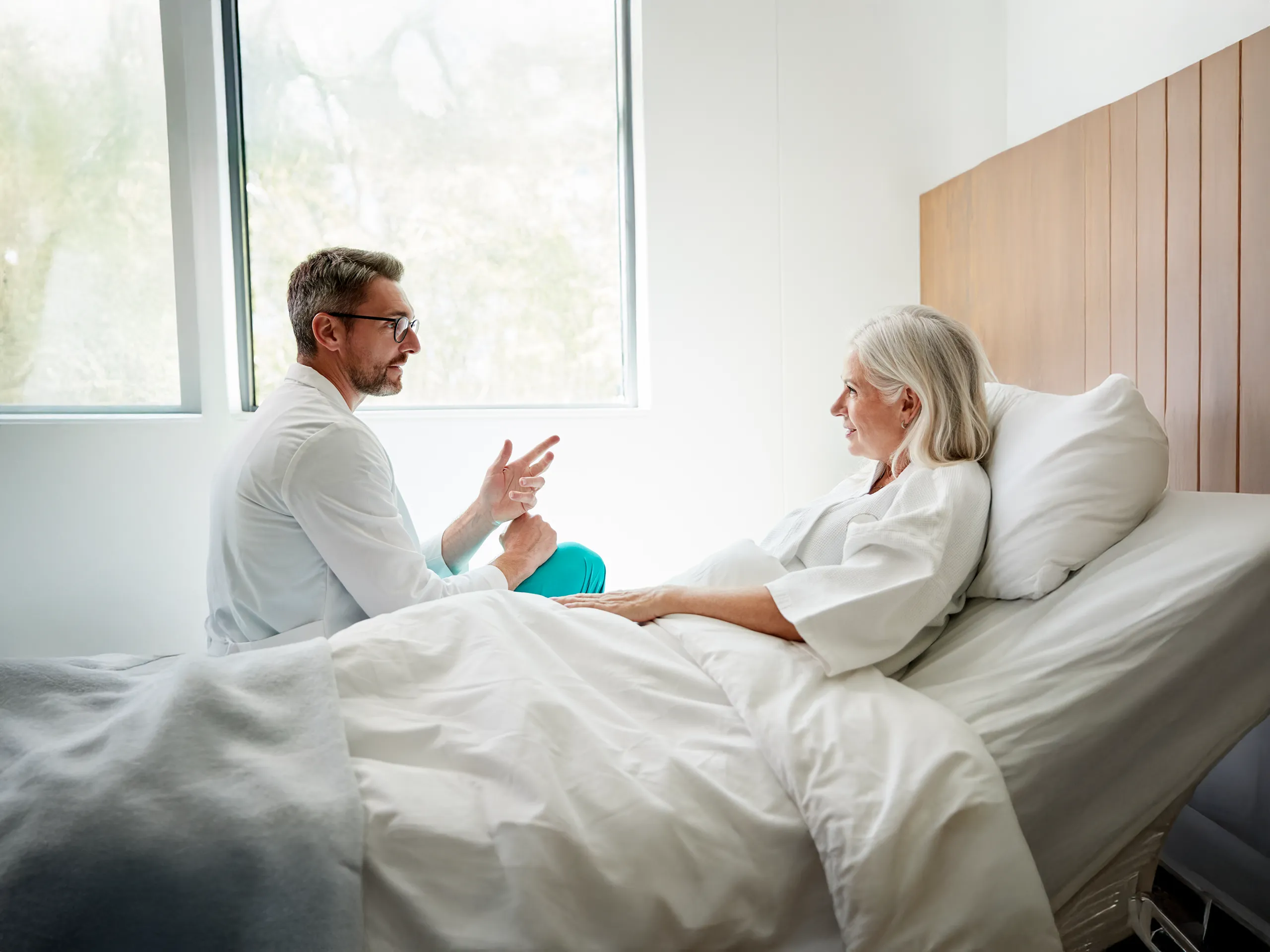 Un médico habla con una paciente anciana en la cama de un hospital.