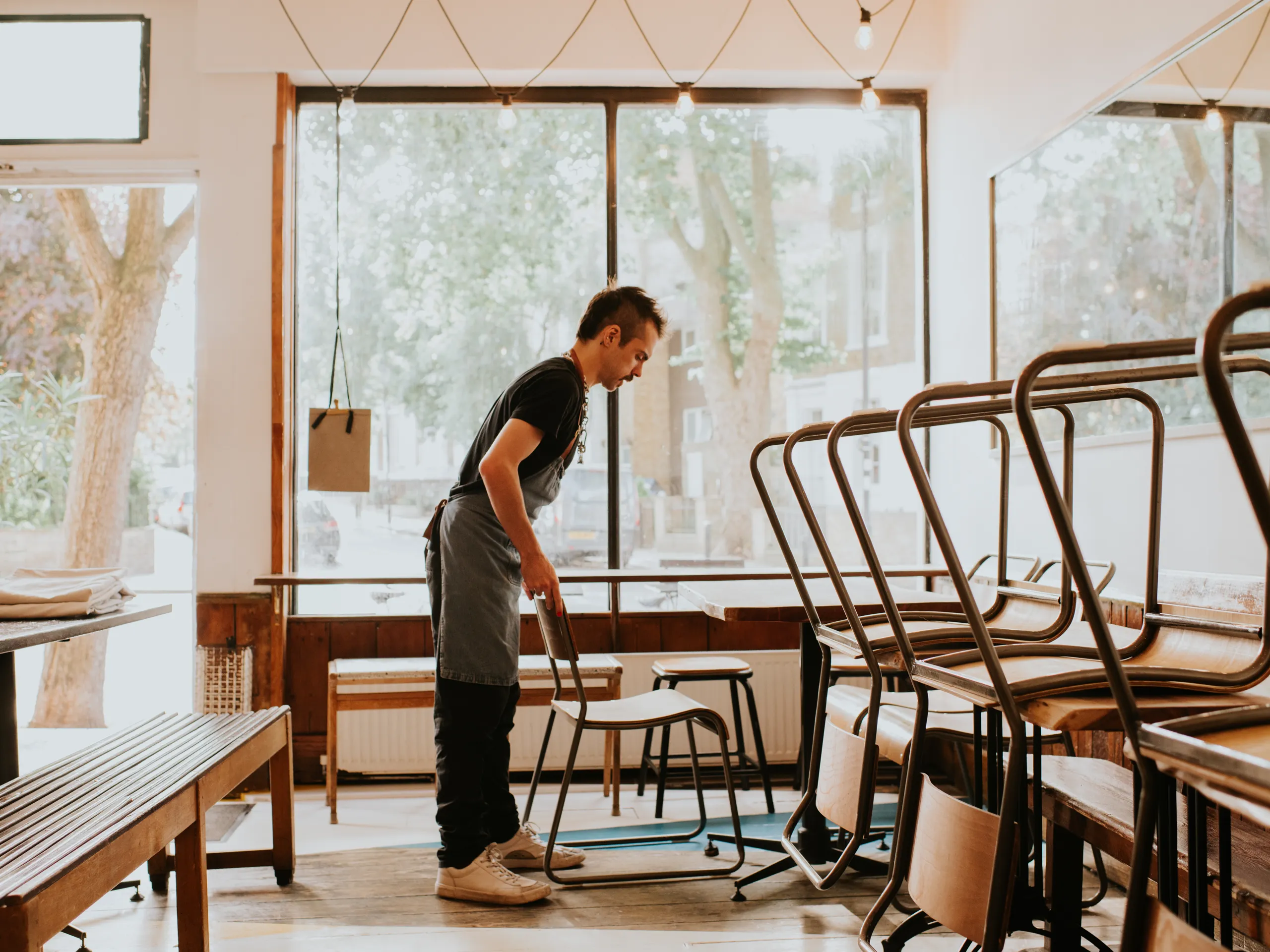 El propietario ordena las sillas en el café.
