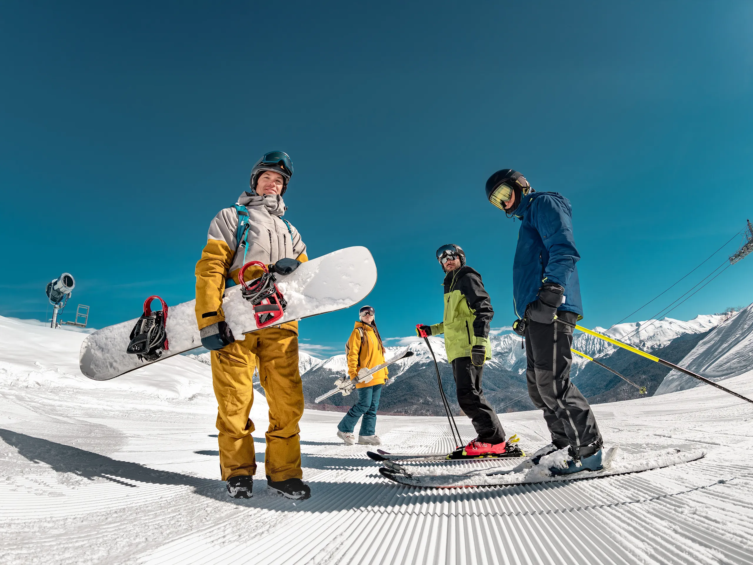Grupo de personas con tablas de snowboard y esquís en una pista de esquí..