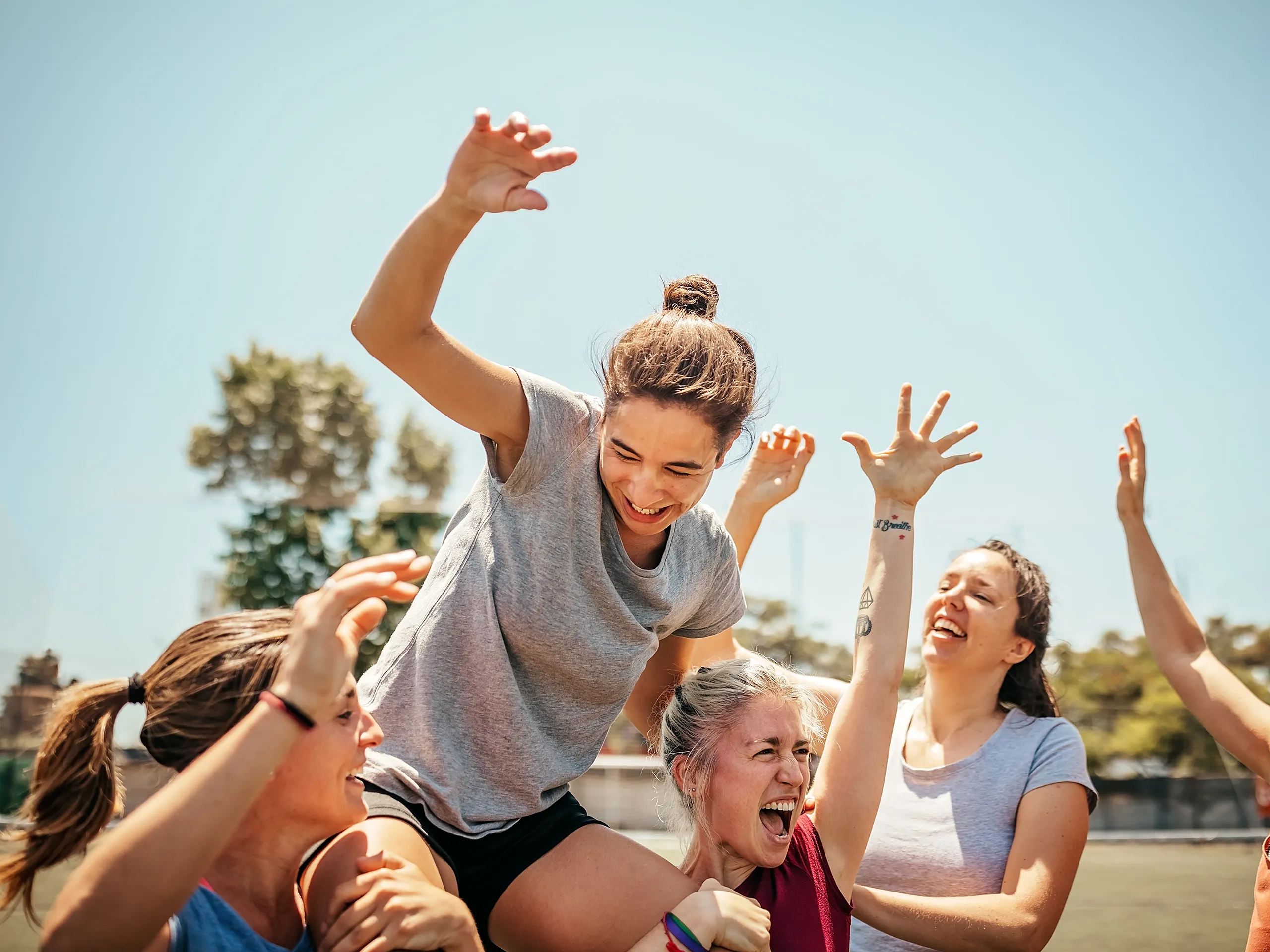 Grupo de mujeres celebran juntas en un campo deportivo.