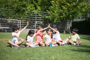 Grupo de niños multiétnicos sentados en el césped, interactuando entre ellos