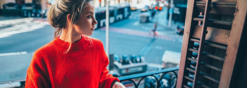 Mujer joven blanca en balcón leyendo un libro