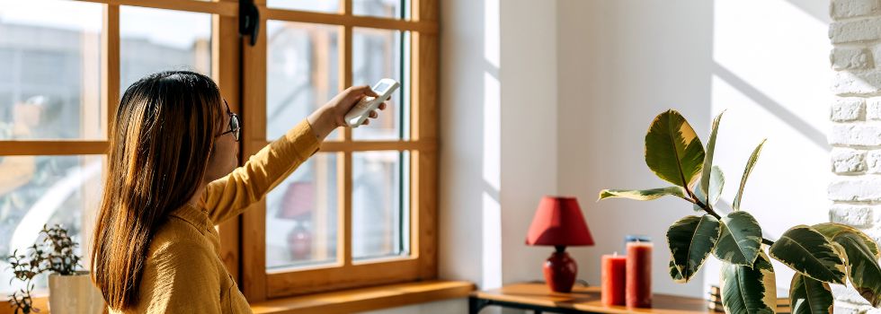 Mujer en su casa encendiendo el aire acondicionado