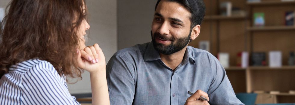 Hombre indio en oficina entrevistando a mujer blanca