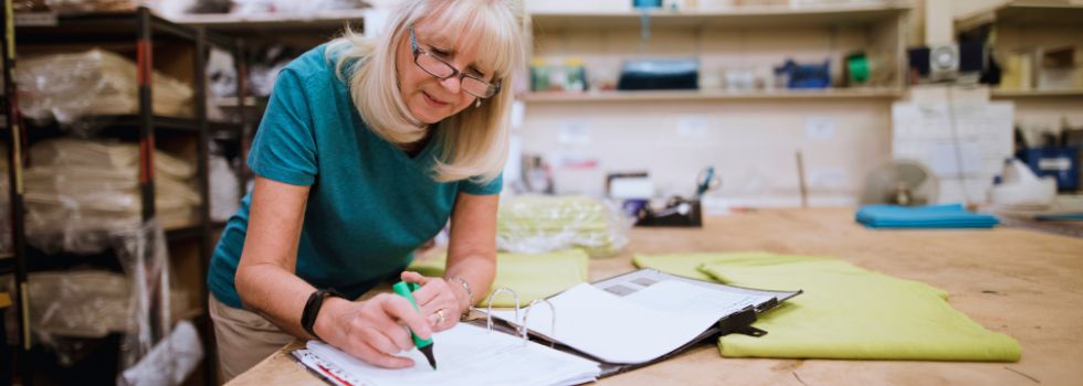 Mujer mayor empresaria anotando datos en su taller