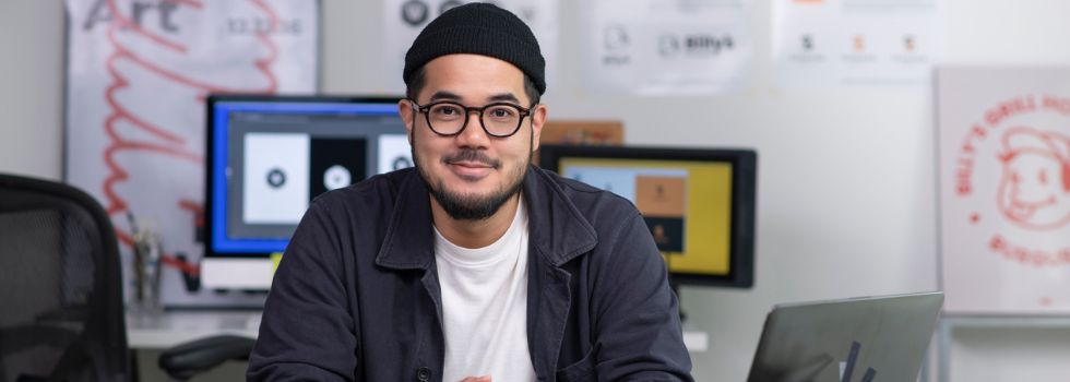 Diseñador hombre asiático en su estudio sonriendo a cámara