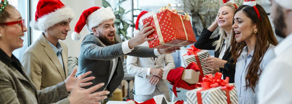 Grupo de trabajadores de una empresa intercambiando regalos en la oficina