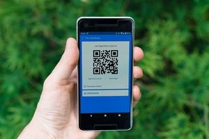 Manos sujetando un móvil y enseñando la pantalla a cámara: un código QR
