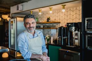 Hombre blanco maduro con delantal en la barra de un bar