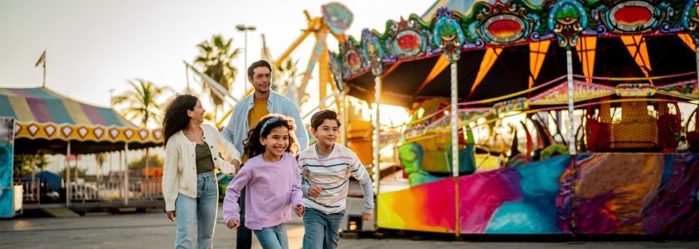 Familia latina compuesta por padre, madre, hijo e hija recorriendo una feria en una Fiesta Mayor