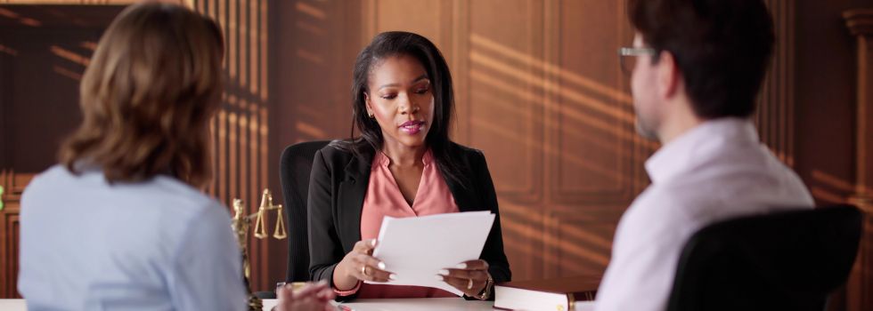 Mujer profesional legal negra habla con dos clientes blancos en su despacho