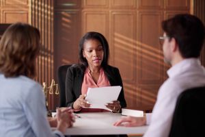 Mujer profesional legal negra habla con dos clientes blancos en su despacho 