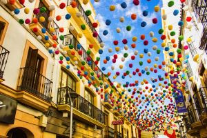 Calle de pueblo en España con banderines de colores colgados de las fachadas