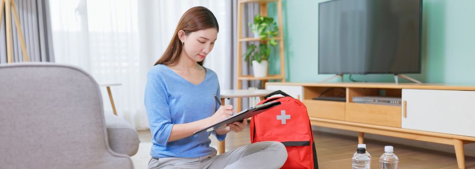 Mujer sentada en el suelo con material para su kit 72 horas