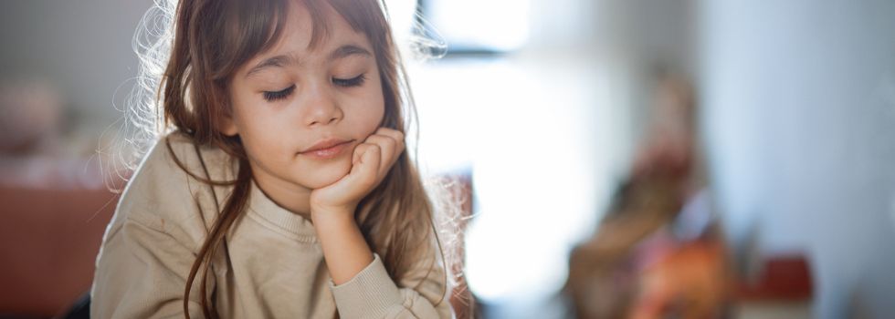 Niña blanca leyendo con el libro apoyado en una mesa