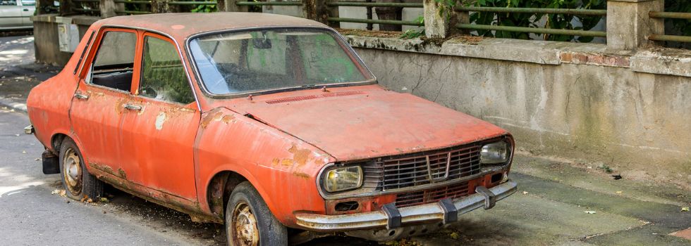 coche rojo antiguo oxidado abandonado en la calle