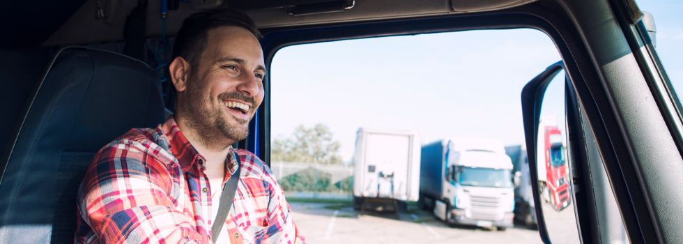 Hombre blanco al volante de un camión sonriente