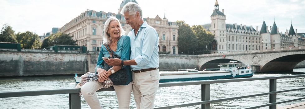 Pareja de hombre y mujer blancos de la tercera edad posando sonrientes frente al Sena