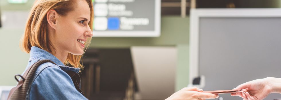 Mujer blanca sonriente entregando pasaporte en el control del aeropuerto